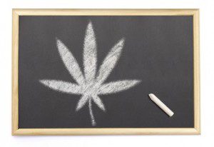 Blackboard with a chalk and the shape of the cannabis symbol dra