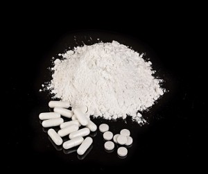 drug powder tablets and capsules close-up on black background.